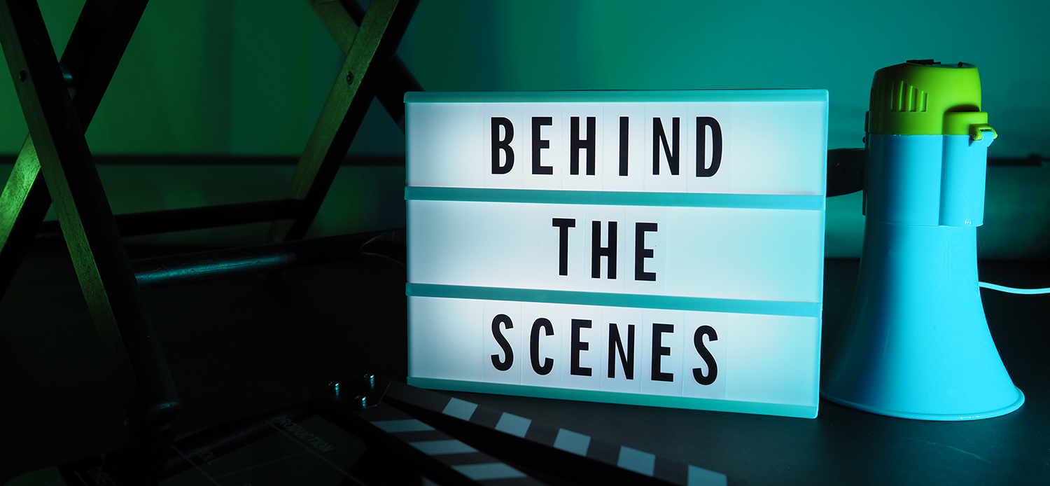 Behind the scenes text on letterboard Lightbox or Cinema Light box. Movie clapperboard or film slate megaphone and director chair beside. Background LED color. shoot in video production studio.